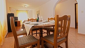 A dining area with a wooden table set for four, surrounded by chairs with cushioned seats. - Apartment 1382 (Marcana)