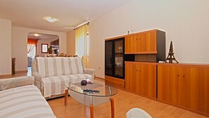 A living room with a sofa, a glass coffee table, wooden cabinets, and a small Eiffel Tower model. - Apartment 1382 (Marcana)