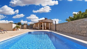 Une piscine avec un mur en pierre et un bâtiment en arrière-plan.