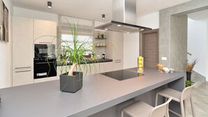 Une cuisine moderne dotée d’un îlot central, d’appareils électroménagers intégrés et d’un design minimaliste.