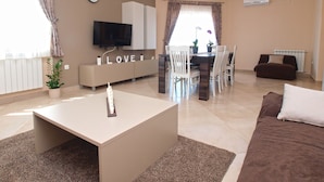 A modern living room with a flat-screen TV, a dining area with a table and chairs, a sofa, and a coffee table. - Apartment 1386 (Vodnjan)