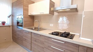 A modern kitchen with wooden cabinets, a stainless steel sink, and a gas stove. - Apartment 1386 (Vodnjan)