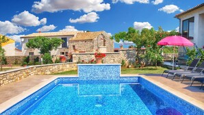 A swimming pool with a mosaic tile design, surrounded by stone walls and potted plants. - Apartment 1386 (Vodnjan)