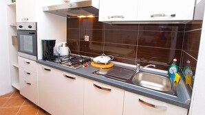 A kitchen with white cabinets, a gas stove, a kettle, and a sink. - Apartment 1388 (Vodnjan)