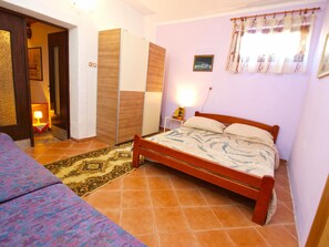 A bedroom with a bed, a nightstand, a lamp, a wardrobe, and a patterned rug.