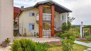 Une maison à deux étages avec un balcon, des plantes en pot et un jardin.