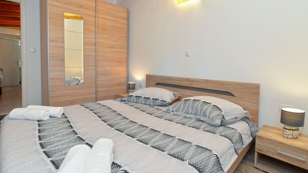 Une chambre à coucher avec un lit en bois, une table de chevet, une lampe de chevet et un luminaire fixé au mur.