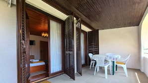 Una habitación con cama, una pequeña mesa con sillas, techo de madera y vistas al exterior.