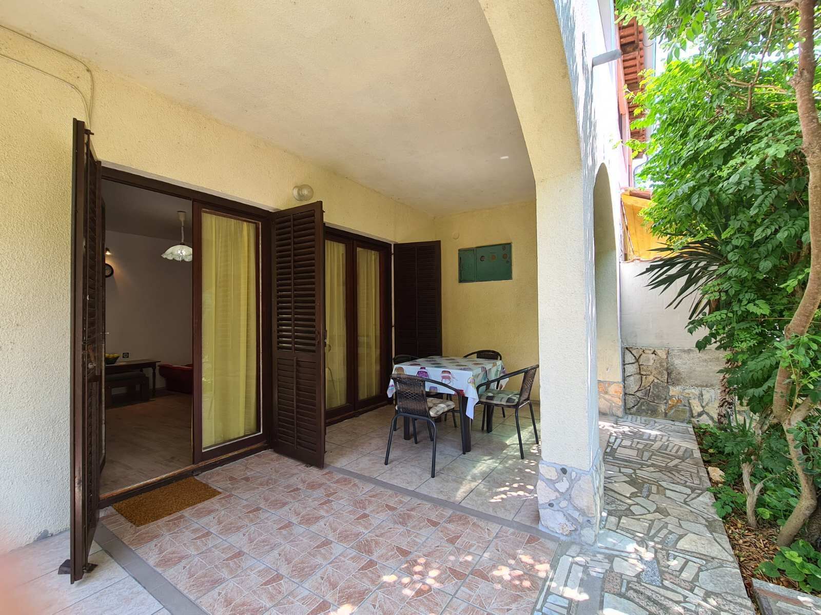 A patio area with a table and chairs, a door leading to another room, and a stone pathway.