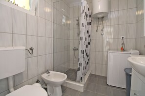Moderni kylpyhuone, jossa on wc, bidee, suihku ja pesuallas.