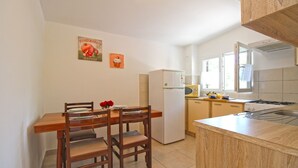Una cocina compacta con mesa, sillas, refrigerador, microondas y estufa.