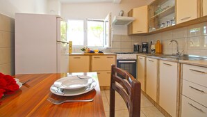 Una cocina moderna con una mesa de comedor para dos personas, estufa, horno y ventana con vistas.