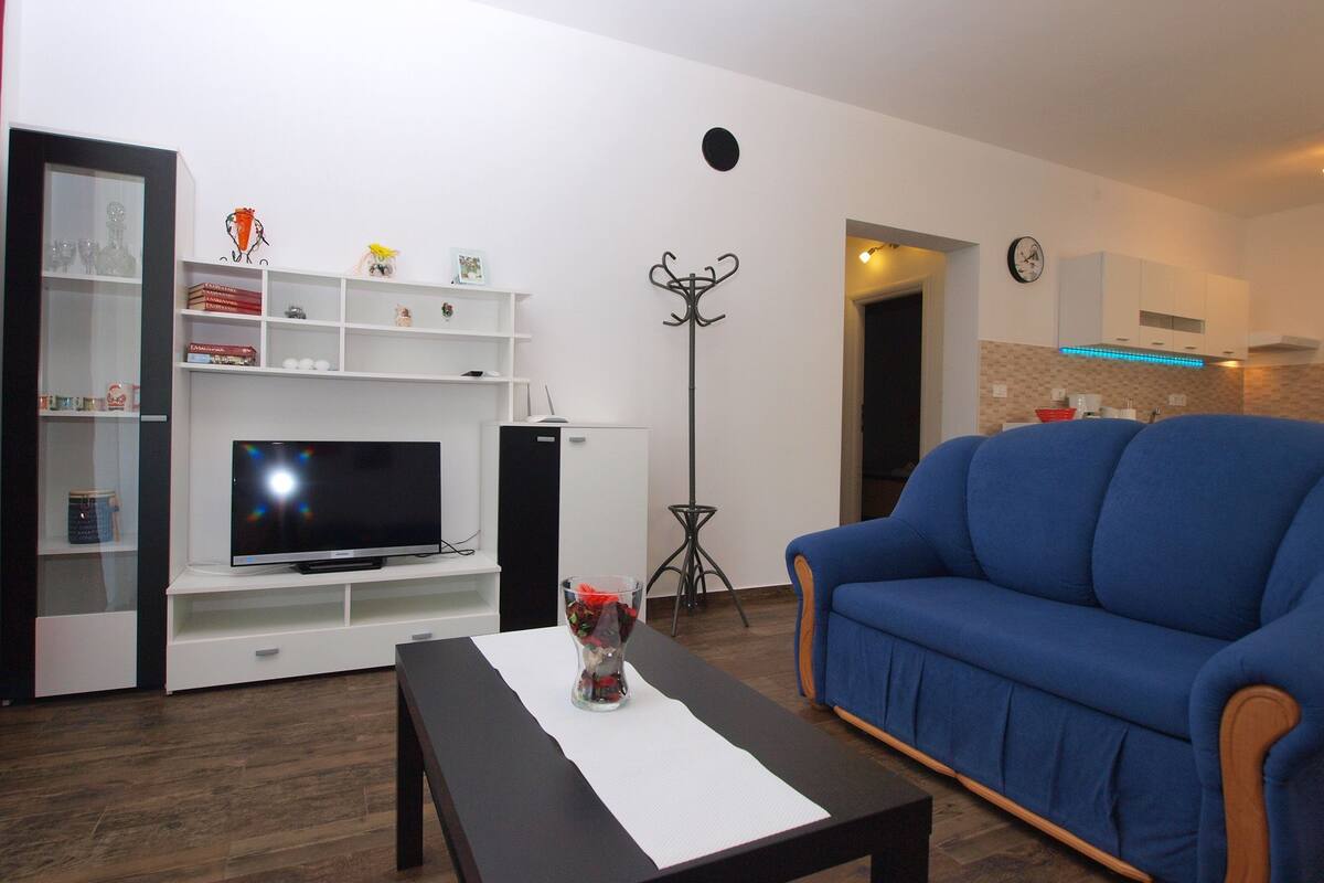 A living room with a TV, sofa, coffee table, and a bookshelf.