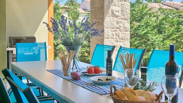 A table set with a bottle of olive oil, a glass, a basket of bread, and a vase of lavender. - Villa 1404 (Zminj)