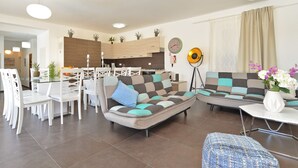 Una sala de estar moderna con un sofá, una mesa de comedor, sillas y una cocina al fondo.