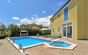 A swimming pool with lounge chairs and umbrellas, surrounded by a stone patio. - Villa 1519 (Zminj)