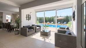 Ein modernes Wohnzimmer mit Blick auf einen Pool, einschließlich einer Essecke und bequemen Sitzgelegenheiten.