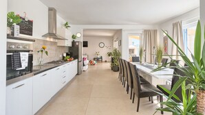 Eine moderne Küche mit weißen Schränken, einer schwarzen Arbeitsplatte und einem Essbereich mit weißem Tisch und Stühlen.