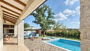 A stone patio with a swimming pool, outdoor seating, and a stone fireplace. - Villa 1521 (Zminj)