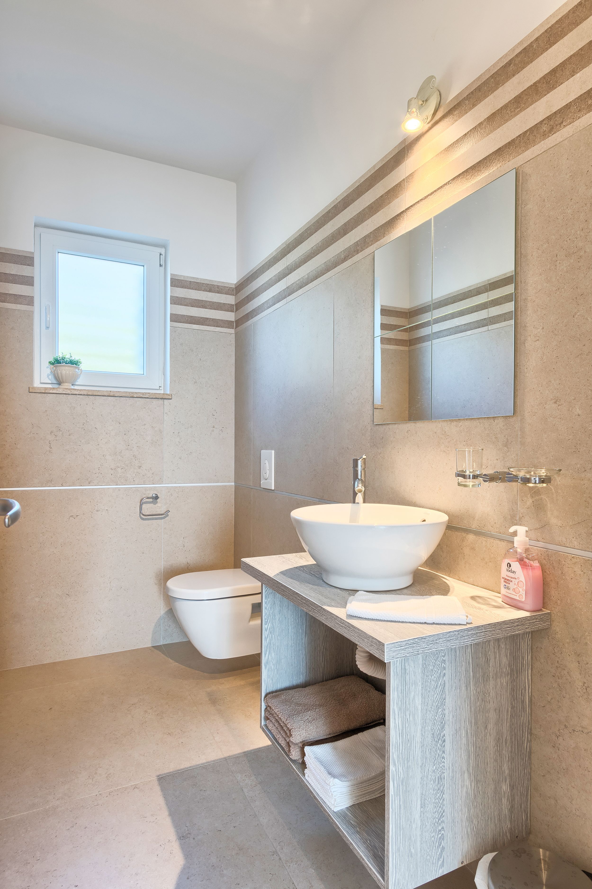 A modern bathroom with a large white sink, a mirror, and a toilet.