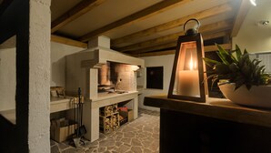 A stone-floored kitchen with a built-in oven, wooden beams, and a lantern on a counter. - Villa 1522 (Zminj)