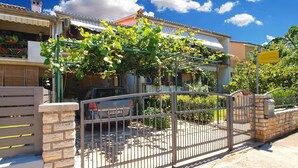 A residential property with a gated entrance, a parked car, and a visible garage. - Apartment 1407 (Fazana)