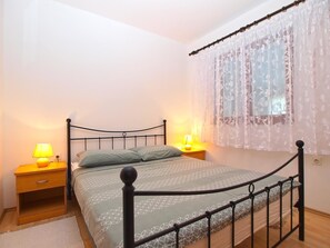 A bedroom with a bed, two bedside tables, and a window with curtains. - Apartment 1407 (Fazana)