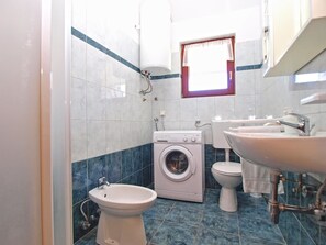 A compact bathroom with a washing machine, toilet, bidet, and sink. - Apartment 1407 (Fazana)