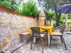 An outdoor patio with stone walls, a brick floor, and a table with chairs. - Apartment 1408 (Medulin)