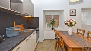 A modern kitchen with a wooden dining table and chairs, a potted plant, and a vase of flowers. - House 1411 (Marcana)