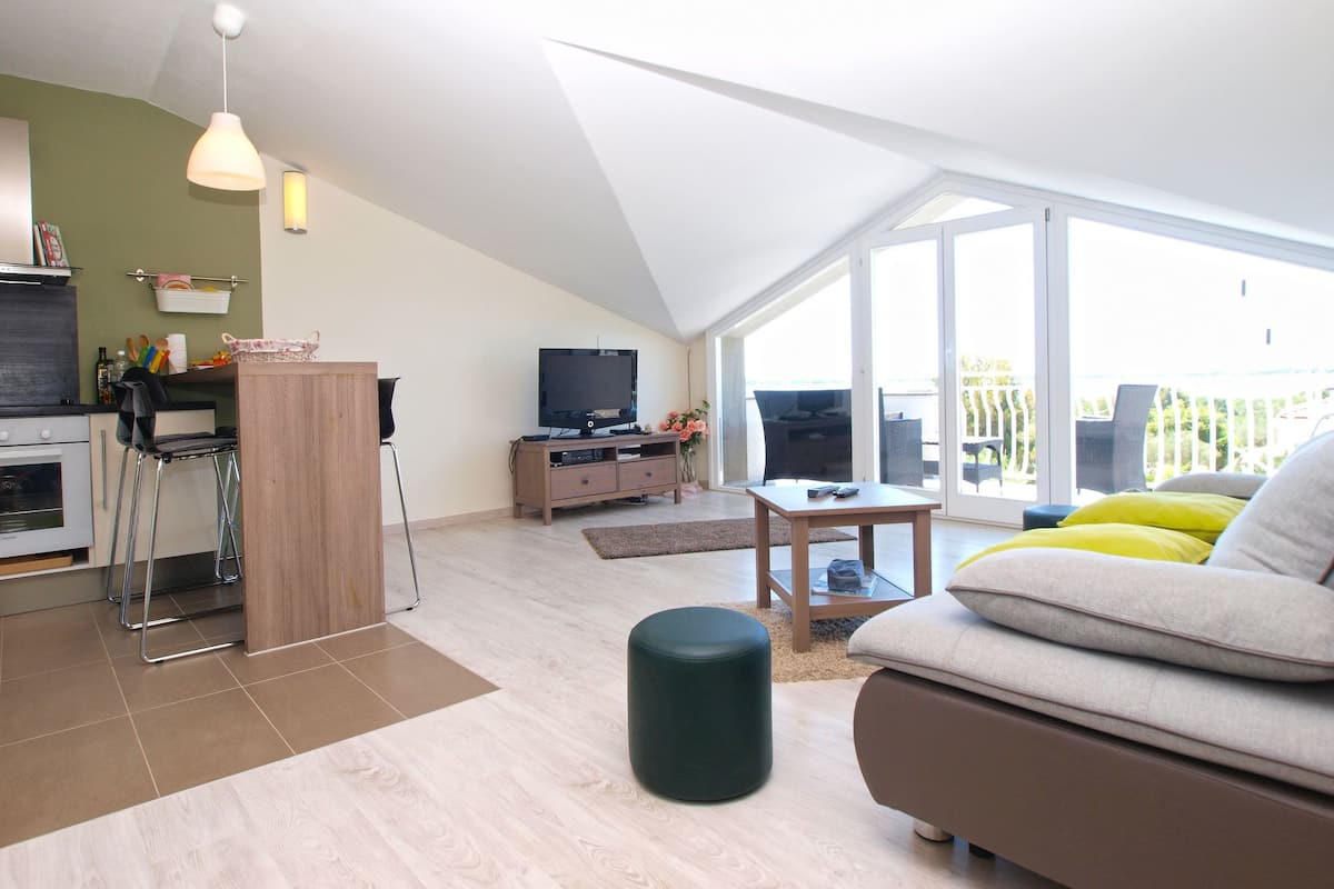 A modern living space with a kitchen, dining area, and a large sliding glass door leading to an outdoor area.