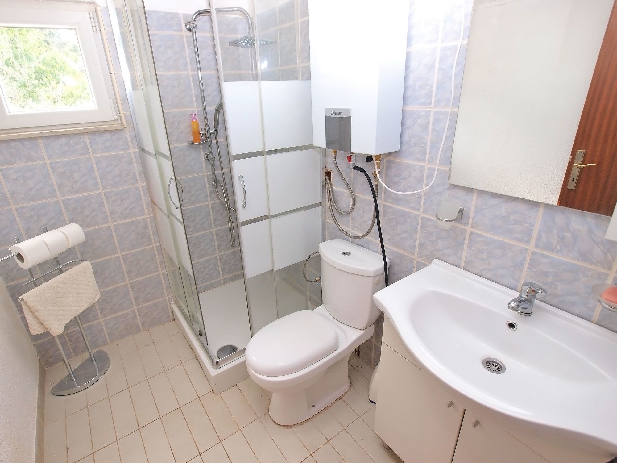 A bathroom with a glass-enclosed shower, a toilet, a sink, and a towel rack.
