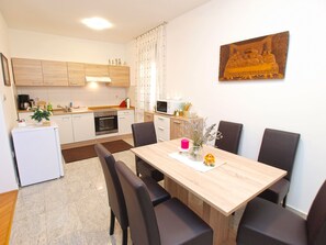 Una cucina moderna con mobili in legno, un frigorifero bianco e un'area pranzo con tavolo in legno e sedie nere.
