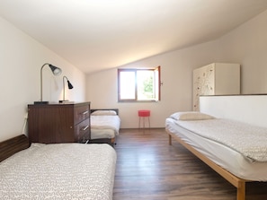 A bedroom with two beds, a dresser, a desk with a lamp, a window, and a wall with a bird mural. - Apartment 1429 (Vodnjan)