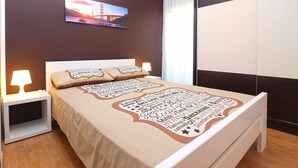 A bedroom with a bed, bedside tables, a lamp, a painting, and a sliding door. - Apartment 1431 (Pula)