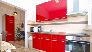 Cocina compacta con armarios rojos, microondas, cafetera y estufa.