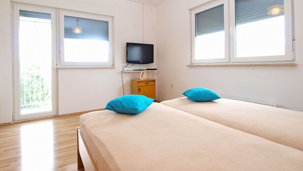 Una habitación con dos camas, televisión y ventana.