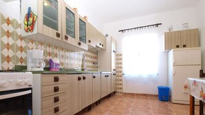 Une cuisine équipée d’une cuisinière, d’un four, de placards et d’une fenêtre avec des rideaux.