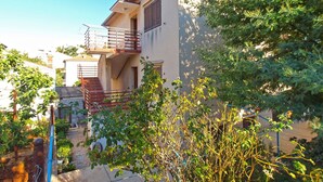 Un immeuble résidentiel doté d’un balcon, d’un escalier et entouré de verdure.