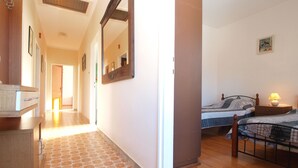 Un couloir au sol décoré de motifs qui mène à une chambre avec deux lits et une table de chevet.