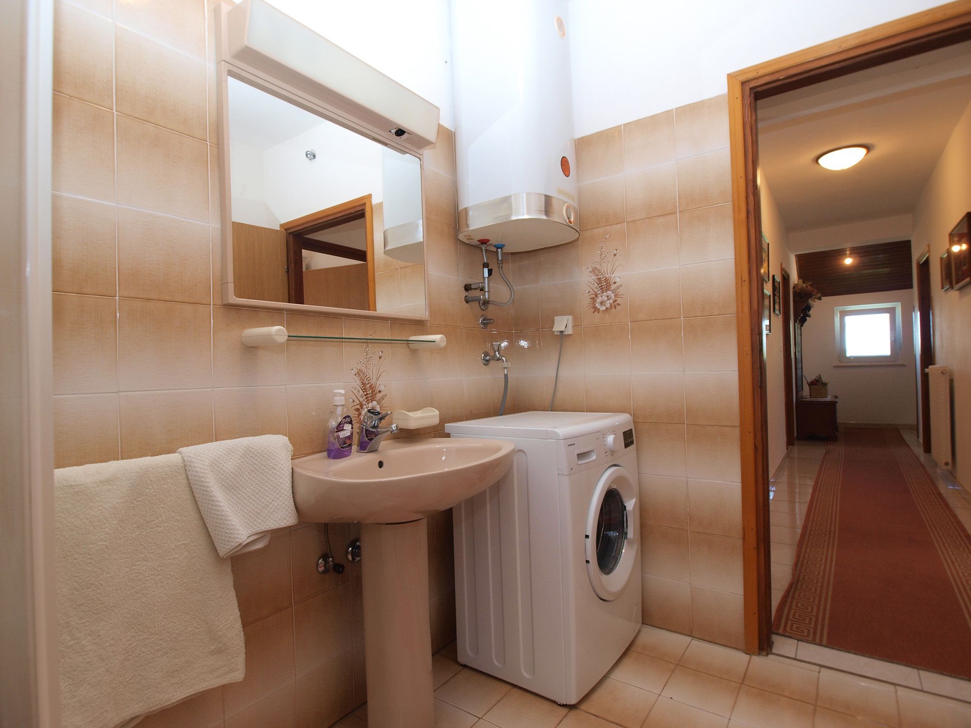 Une petite salle de bain comprenant un lavabo, un miroir et un lave-linge.