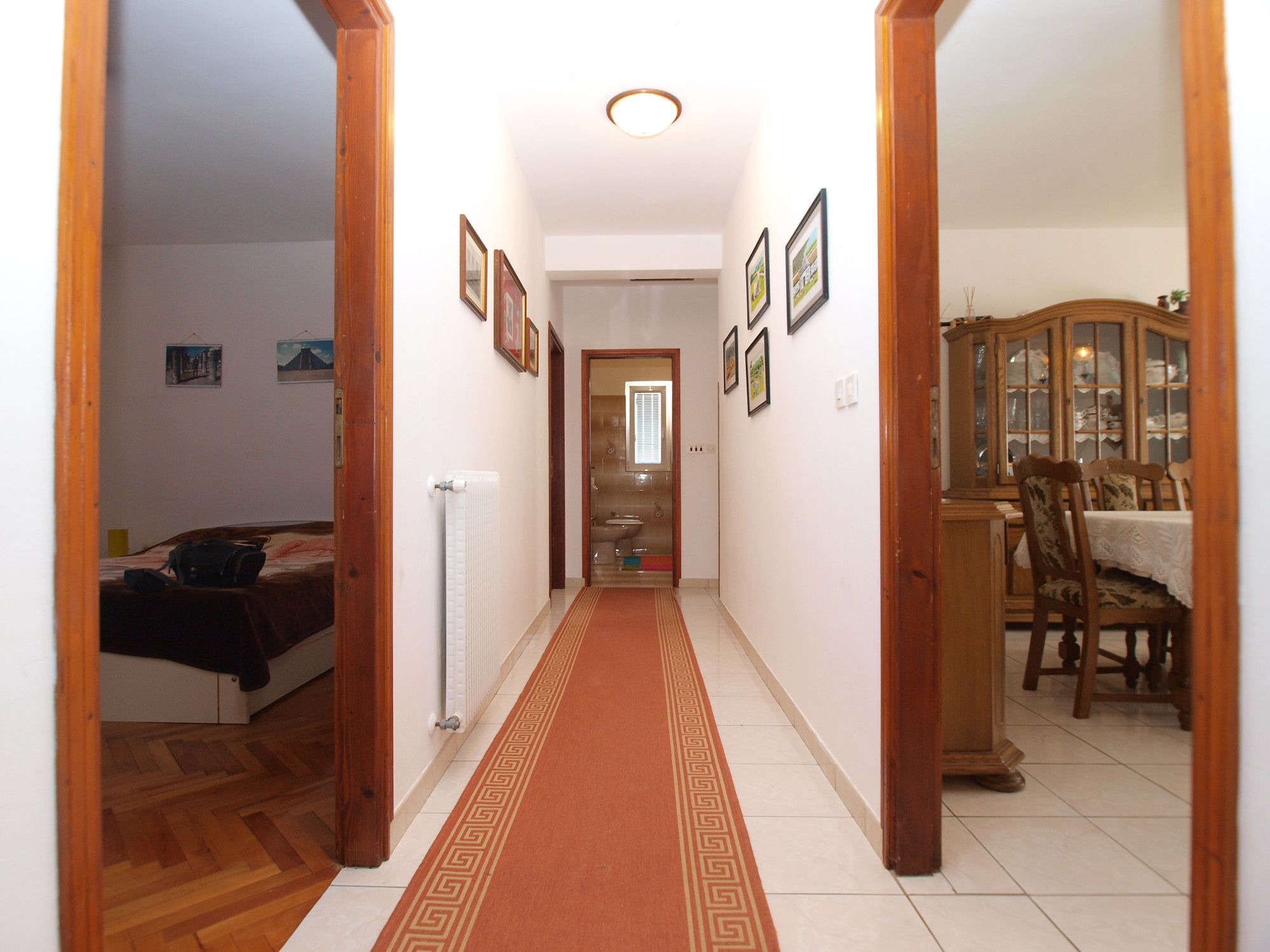 A hallway with a patterned carpet, wooden doors, and framed pictures on the walls.