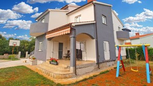 A two-story house with a balcony, a chimney, and a basketball hoop in the yard. - Apartment 1449 (Pula)