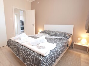 A neatly made bed with a patterned bedspread, a white headboard, and a bedside lamp.