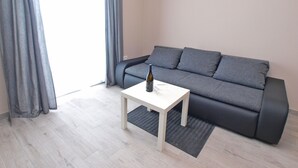 A modern living room with a grey sofa, a white coffee table, and a bottle of wine. - Apartment 1449 (Pula)