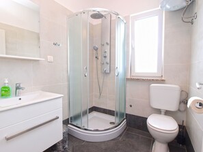 A modern bathroom with a glass-enclosed shower, a white sink, and a toilet. - Apartment 1449 (Pula)