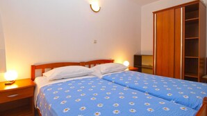 Een slaapkamer met een tweepersoonsbed, twee bedlampen, een houten garderobe en een nachtkastje.