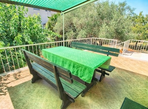 An outdoor patio with a green table and benches, surrounded by a metal railing and greenery. - Apartment 1457 (Rovinj)