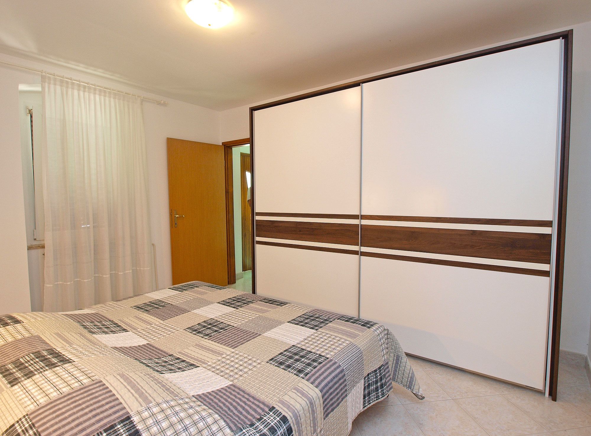 A bedroom with a bed, a wardrobe, and a door.