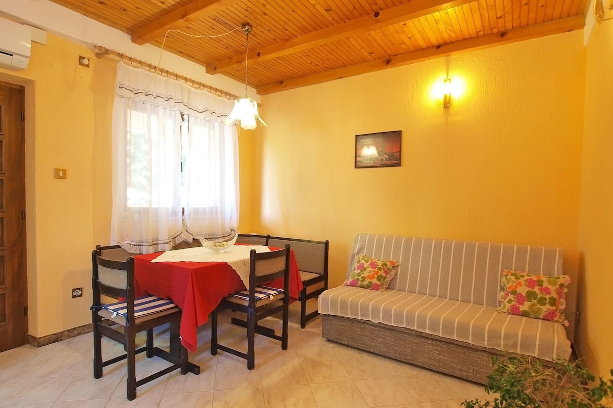 Un comedor con techo de madera, una mesa con mantel rojo, dos sillas y un sofá con cojines a rayas.
